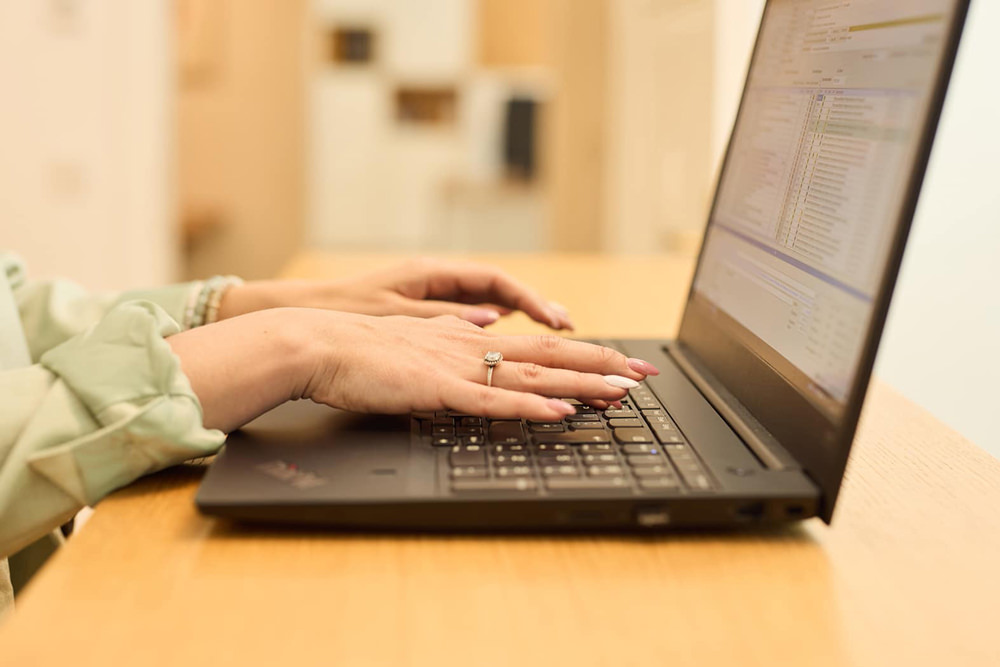 Digitaler Arbeitsplatz im Medizincontrolling Hände einer Mitarbeiterin bei der Arbeit an einem Laptop im Bereich Medizincontrolling.